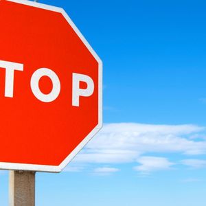 Achtkantiges rotes Stoppschild vor blauem Himmel.