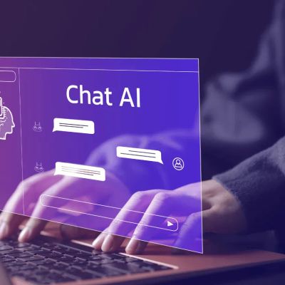 „Chatbot-Fenster mit der Aufschrift 'Chat AI' über zwei Händen, die auf einer Laptop-Tastatur tippen.“