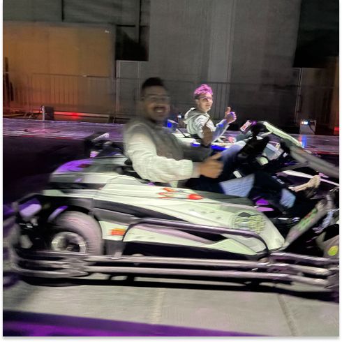 Zwei Personen fahren nachts in Karts und zeigen Daumen nach oben.