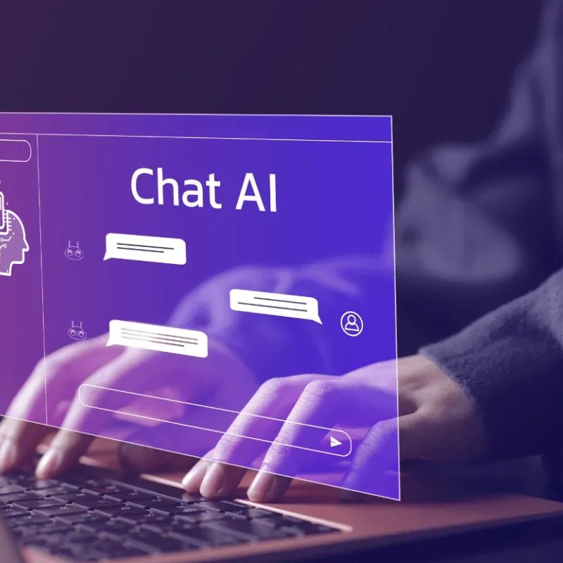 „Chatbot-Fenster mit der Aufschrift 'Chat AI' über zwei Händen, die auf einer Laptop-Tastatur tippen.“